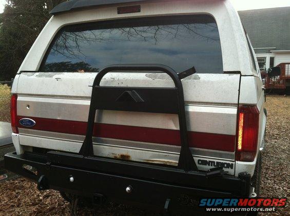 Rear view of a white Ford Bronco Centurion Conversion with a black rear bumper and spare tire carrier