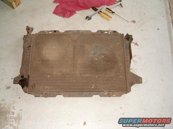 Radiator with bent fins and rust, lying on a concrete floor