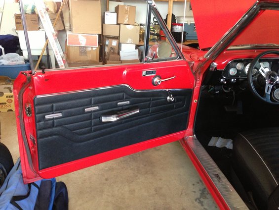 1964 Ford Fairlane interior showing red door frame and black door panel with chrome trim