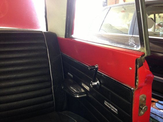 Interior shot of a car's back seat and door panel. Another car is visible through the window