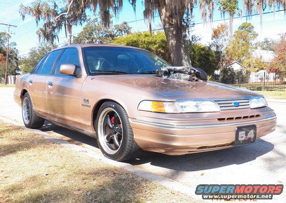 Gold 1993 Ford Crown Victoria with a supercharger protruding from the hood, parked on a street