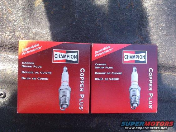 Two boxes of Champion Copper Plus spark plugs sitting on a dark surface