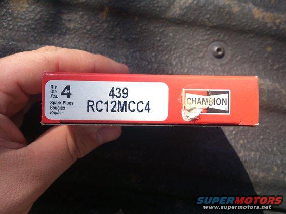 Box of four Champion RC12MCC4 spark plugs held by a hand