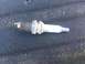 2004 Dodge 1500 - A used spark plug, possibly from a Dodge 1500, is shown against a dark, textured background.