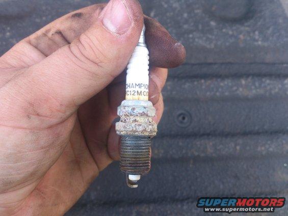 Hand holding a Champion C12MC spark plug with some wear