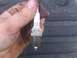2004 Dodge 1500 - A close-up shows a Champion spark plug held in a dirty hand, with visible wear on the electrode.