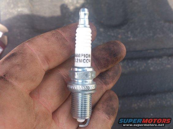 Champion spark plug held in a dirty hand