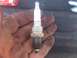 2004 Dodge 1500 - A dirty hand holds a used Champion spark plug, showing signs of wear and tear.