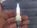 2004 Dodge 1500 - A Champion spark plug, labeled 2M CC4, is held in a hand with dirt on it. The background is out of focus.