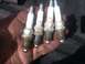 2004 Dodge 1500 - Four used Champion spark plugs, some showing wear and carbon buildup, are held in a hand.