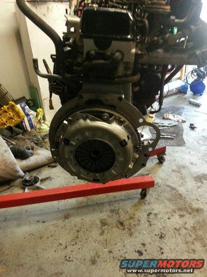 Engine and transmission assembly on a red engine stand, with clutch visible