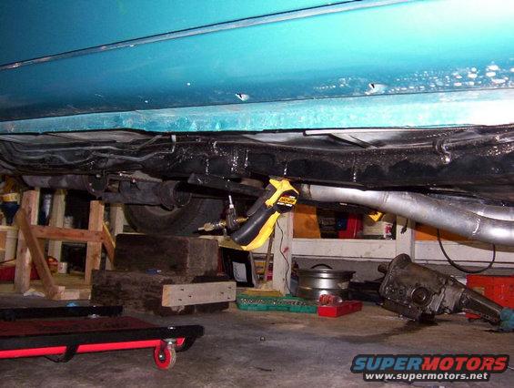 Car underside with exhaust and transmission removed, teal body panel above