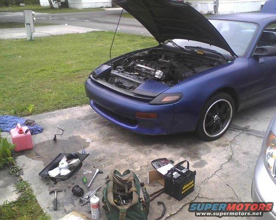 Blue 1991 Toyota Celica with hood open, tools and battery on driveway