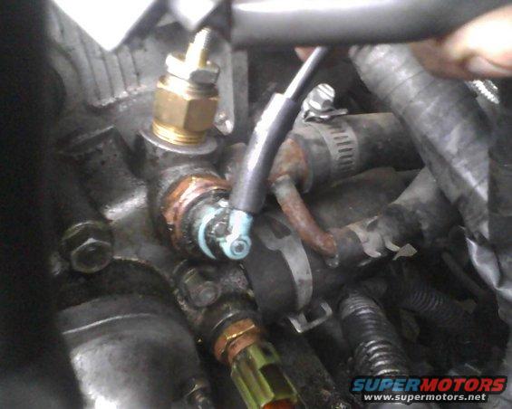 Engine part with brass fitting and blue wire connector
