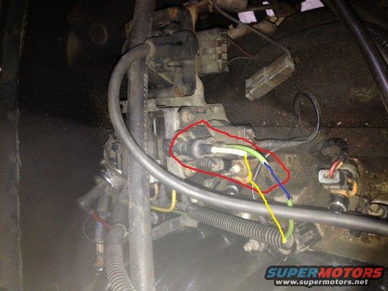Close-up of engine part with red circle highlighting electrical connectors and wires