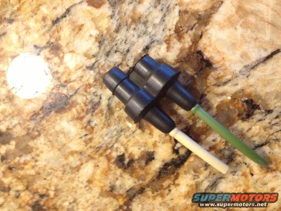Two black electrical connectors with white and green wires attached, resting on a granite countertop