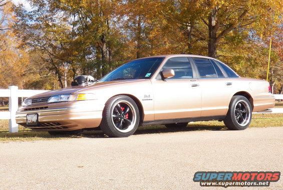 1993 Ford Crown Victoria with aftermarket wheels and hood scoop parked outdoors