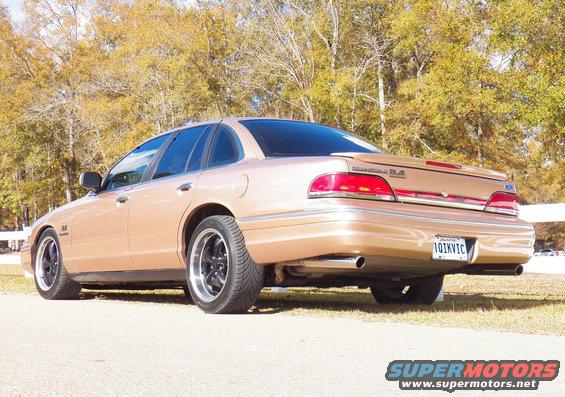 Gold 1993 Ford Crown Victoria with aftermarket wheels, seen from the rear
