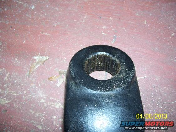 Black splined metal part with a circular opening, resting on a red surface