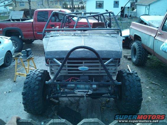 Modified off-road vehicle with roll cage, winch, and large tires. Ford emblem visible on grille
