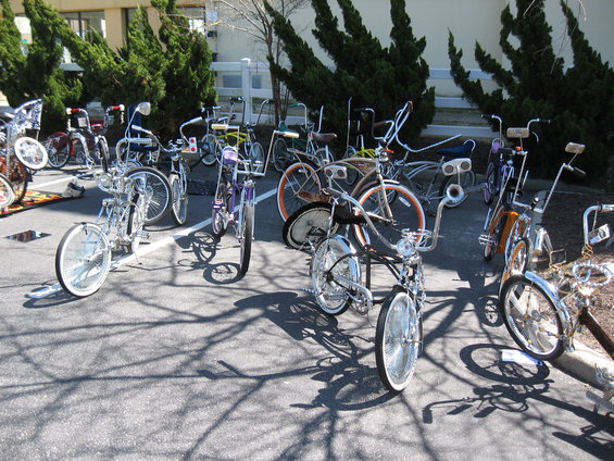 Lowrider bicycles parked on asphalt, some with chrome details and tall handlebars