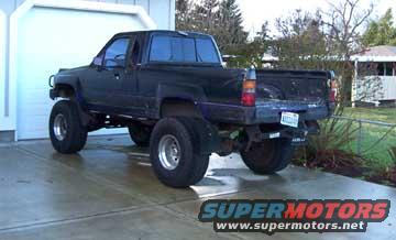 Black pickup truck with dual rear wheels parked in front of a garage