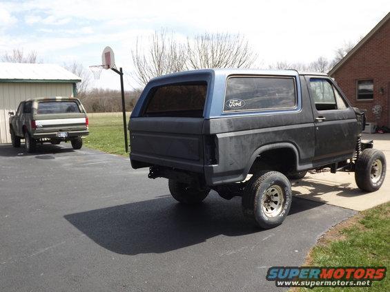 Black Ford Bronco with blue top, lifted suspension, and missing front end