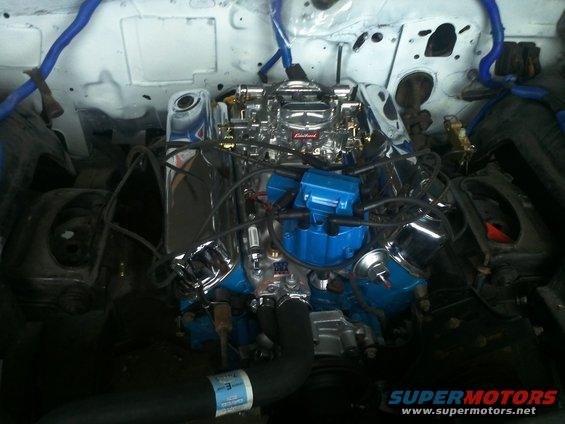Engine bay with a chrome Edelbrock carburetor and blue distributor cap
