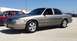 2005 Ford Crown Victoria - Two Ford Crown Victorias parked outside a store on a sunny day.