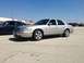 2005 Ford Crown Victoria - A silver sedan is parked in a lot next to a blue sedan under a clear sky.