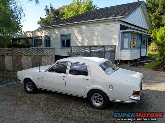 White sedan parked in front of a house, rear quarter view