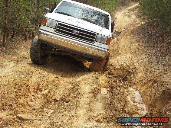 White Ford Bronco stuck in mud on a dirt road