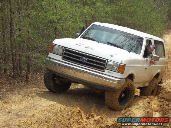 White 1990 Ford Bronco navigating a muddy off-road trail