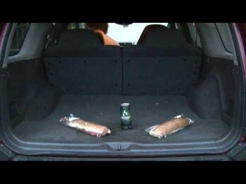 Cargo area of a dark-colored SUV with two sandwiches and a can of soda