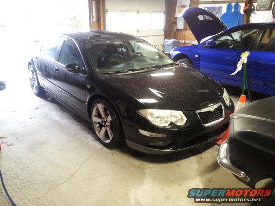Black Chrysler 300M parked in a garage next to a blue car with its hood up