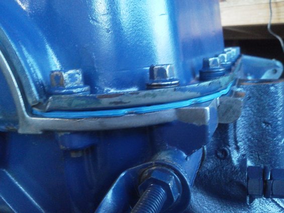 Close-up of a blue engine component with a blue gasket and bolts