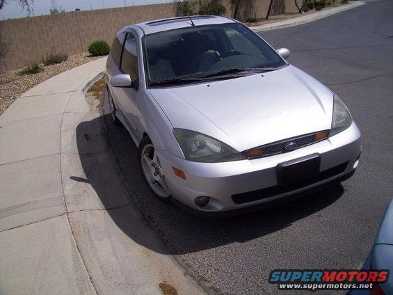 Silver hatchback parked on a street with a concrete curb and sidewalk