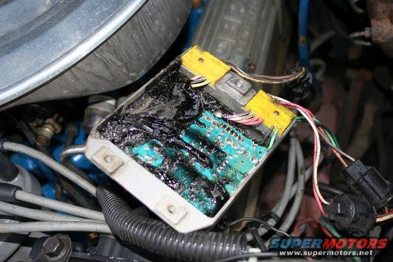 Burnt ignition module with melted black plastic and exposed circuit board, wires connected