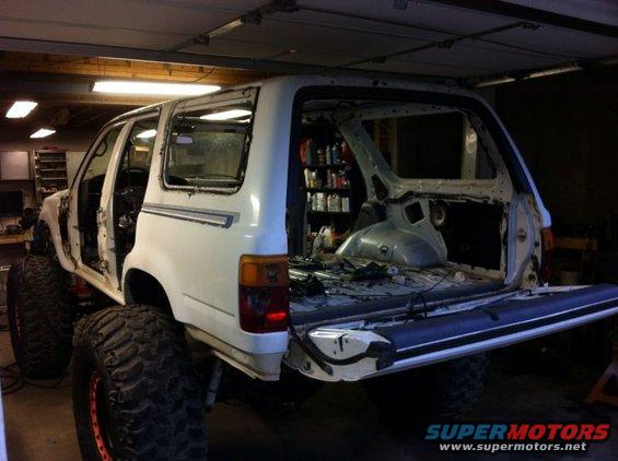 White SUV with large tires, stripped interior, tailgate open. Supermotors.net logo visible