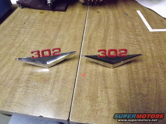 Two chrome and red "302" emblems on a wooden surface