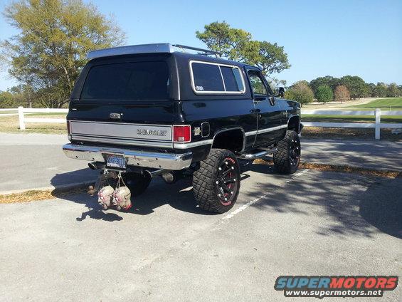 Black 1980 Chevrolet K5 Blazer rear view, lifted with large tires and novelty heads hanging from bumper