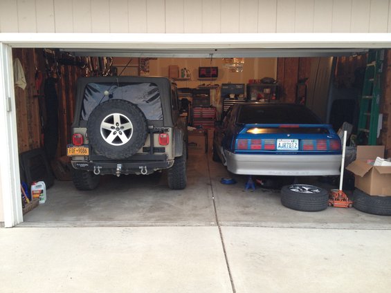 1990 Ford Mustang and Jeep Wrangler in a garage, rear view
