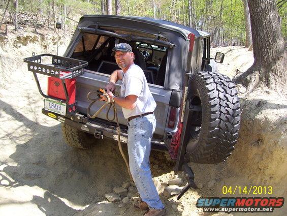 Gray 1990 Ford Bronco with spare tire on rear, on a dirt trail