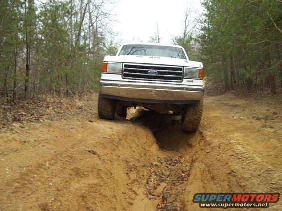 White 1990 Ford Bronco driving on a dirt trail