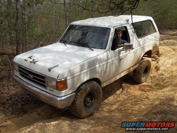White 1990 Ford Bronco off-roading on a dirt trail