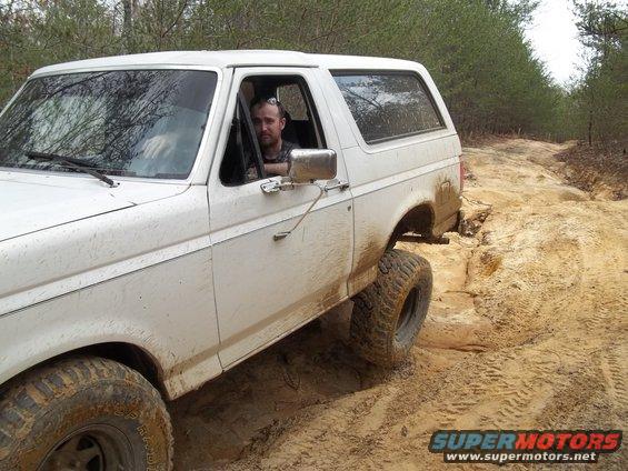 1990 Ford Bronco driving on a dirt trail, driver visible