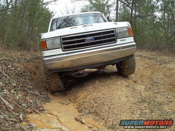 White Ford truck with chrome grille and bumper, driving off-road