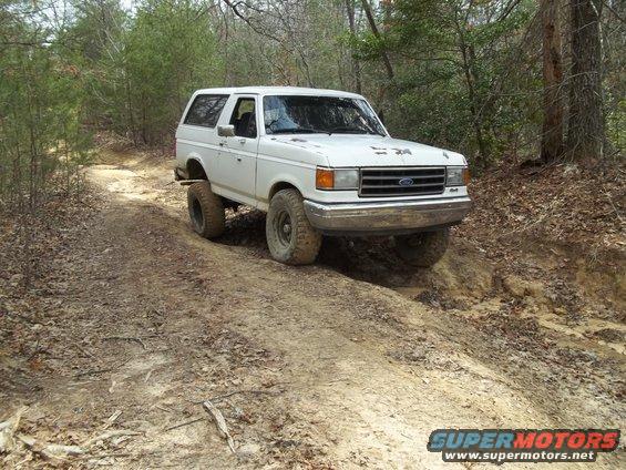 White 1990 Ford Bronco on a muddy trail
