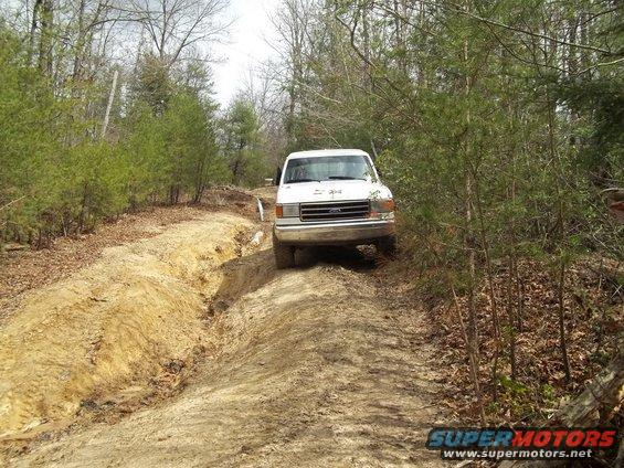 White 1990 Ford Bronco on a dirt path in the woods