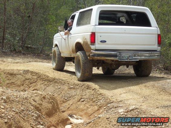 White Ford Bronco driving on a dirt trail, rear view